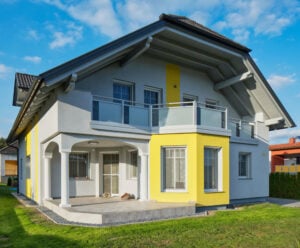 Großzügiges Wohnhaus unter blauem Himmel mit Alu Design Verde Balkon