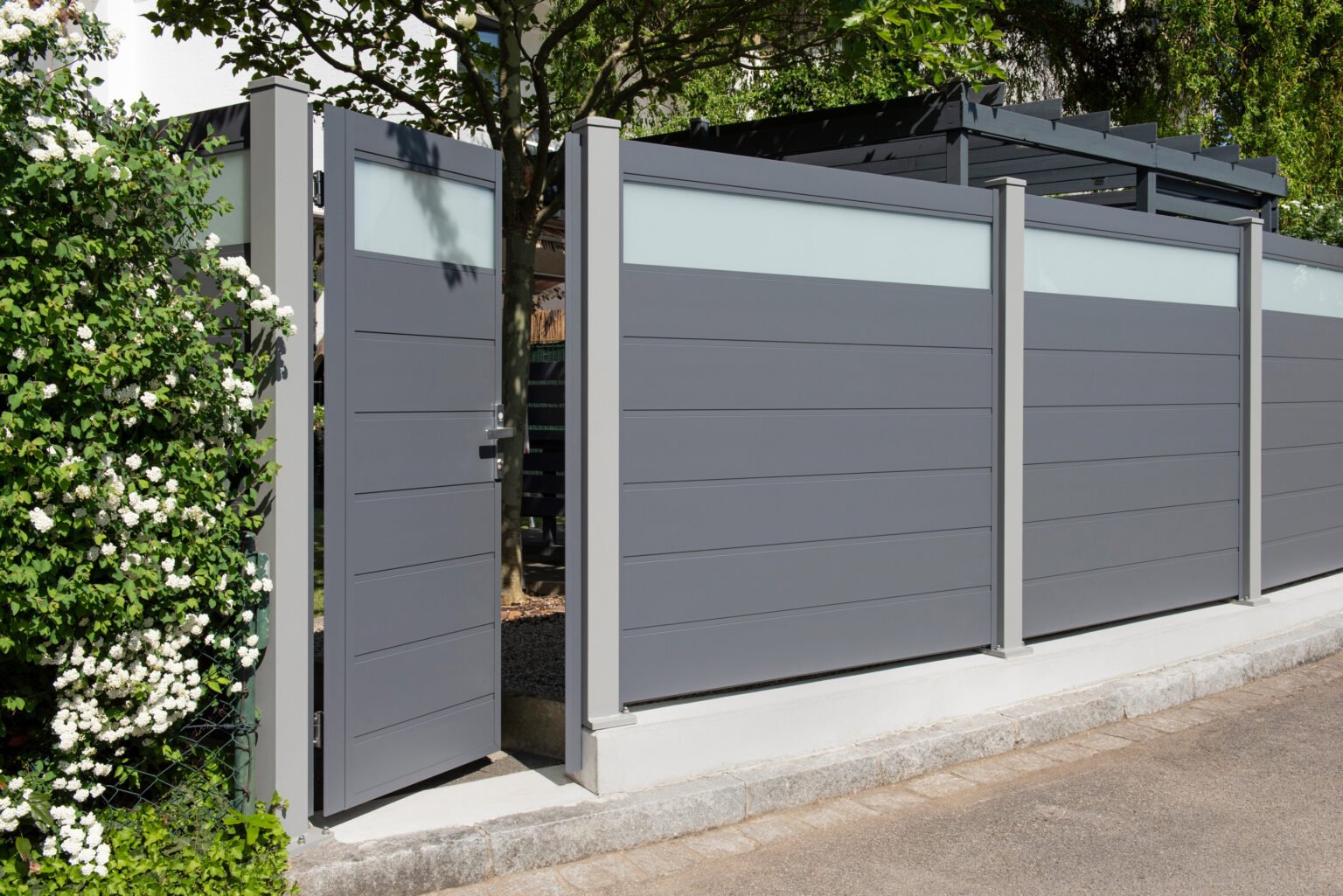 Ein blickdichter Gartenzaun aus Aluminium und Glas mit einer eingebauten Tür.