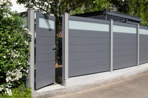 Ein blickdichter Gartenzaun aus Aluminium und Glas mit einer eingebauten Tür.