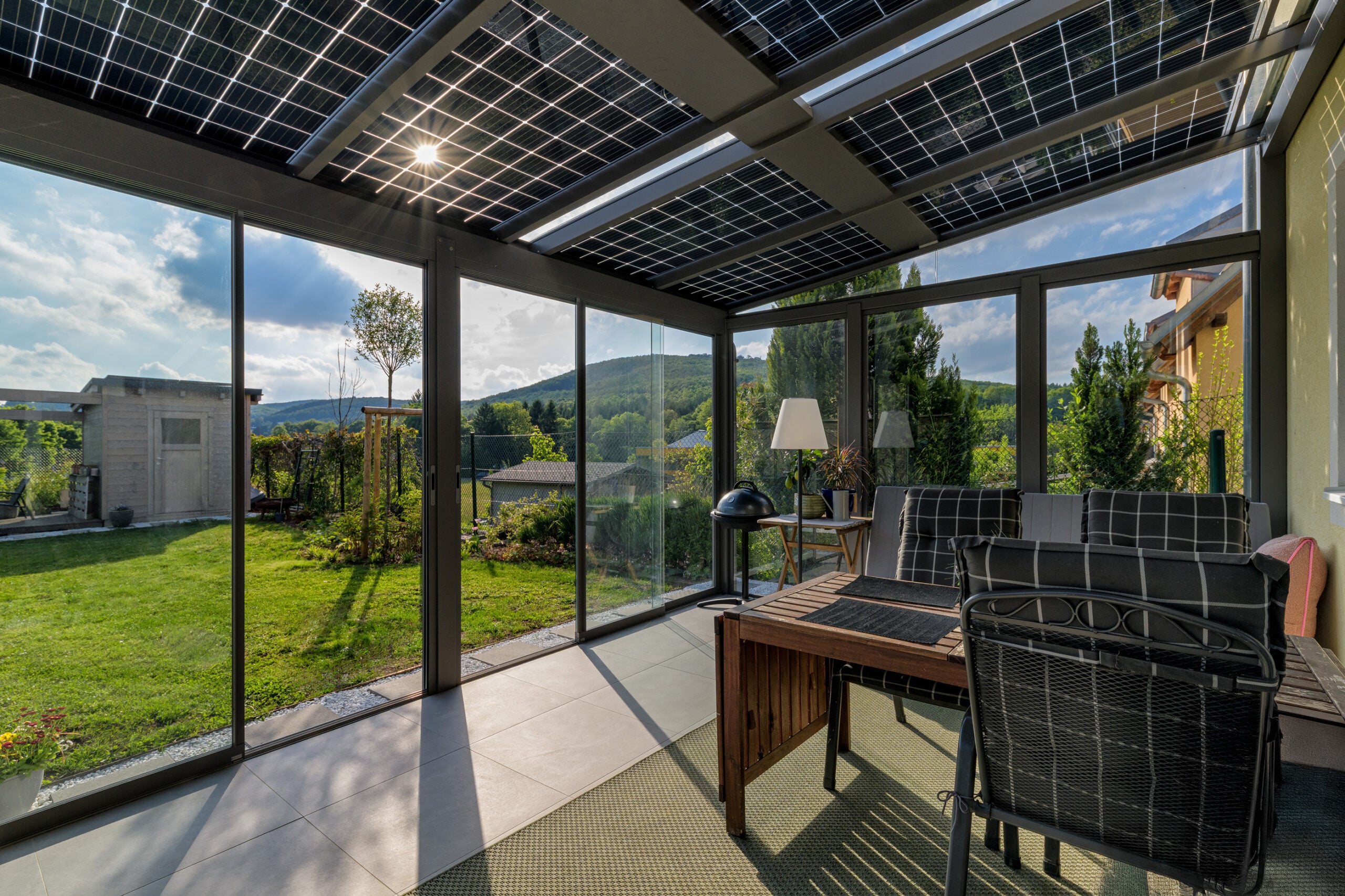Innenansicht unter einem Solardach: Sonnenlicht fällt zwischen den Solarzellen auf Loungemöbel