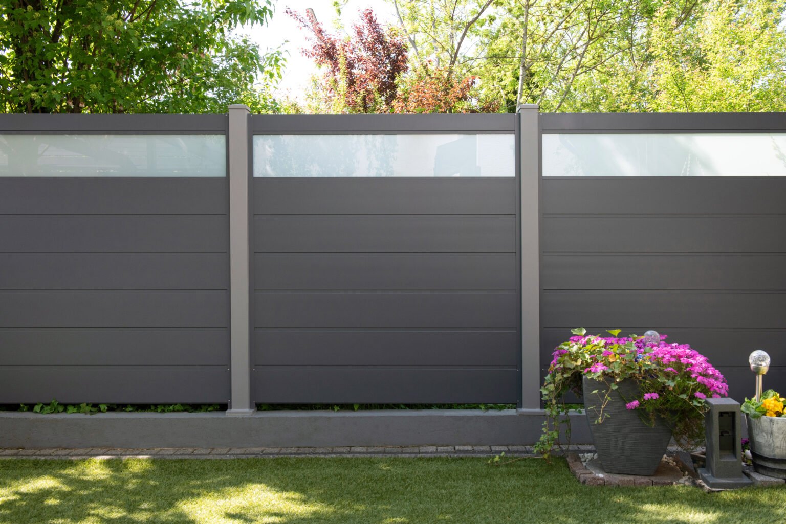 Ein Garten mit einem blickdichten Zaun aus Aluminium und Glas.