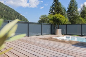 Leeb Geländer Modell Vision mit mattgrauer Glasfüllung - terrassenartiger Balkon modernes Holzhaus, Innenansicht mit verbautem Whirlpool