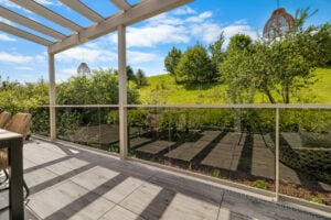 terrassenueberdachung mit einem balkon aus transparentem glas und einem boden aus feinsteinzeug