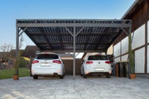 Frontale Aufnahme eines Carports mit Solarpaneelen und zwei weissen Autos