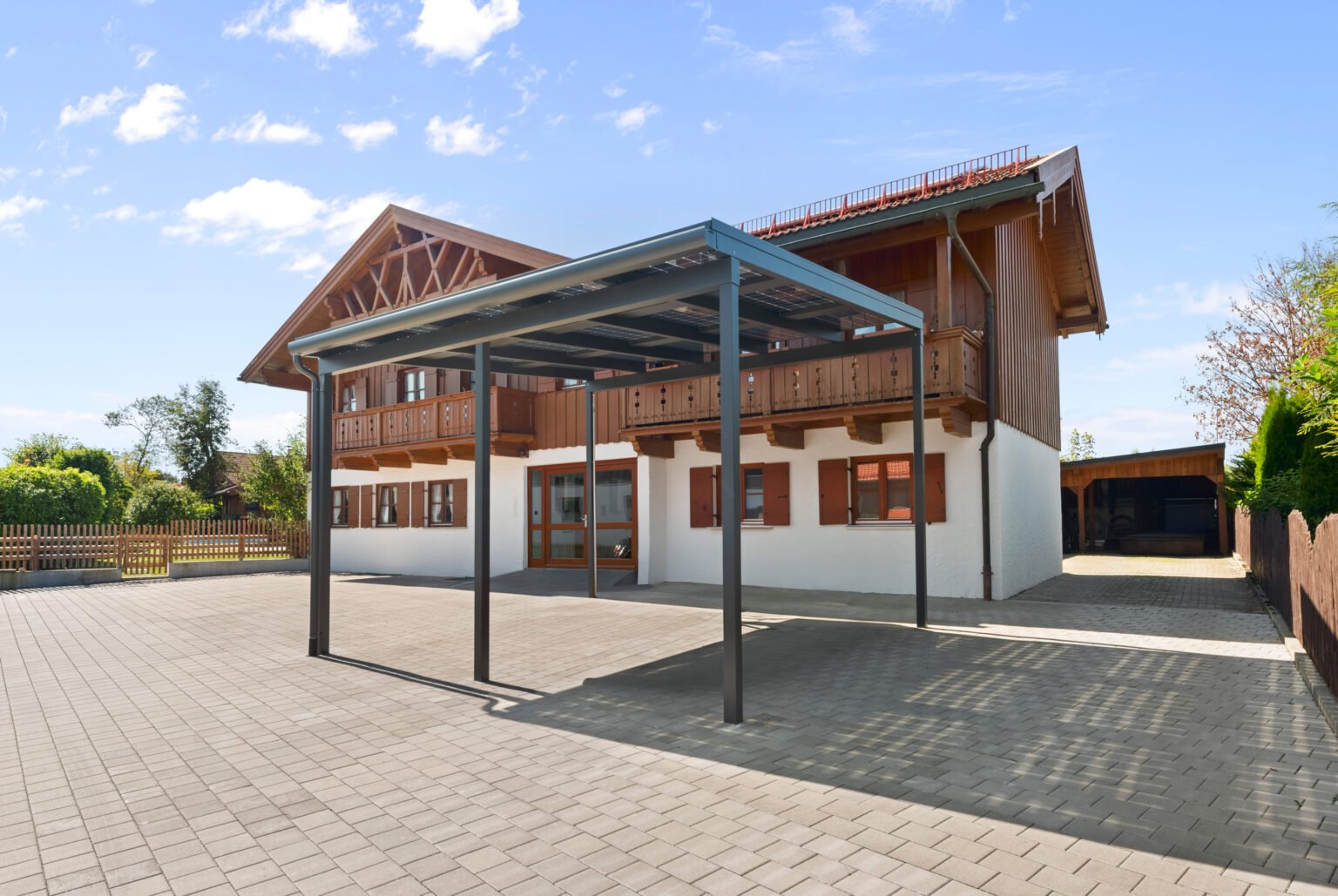 Moderner Solar Doppel-Carport von Leeb in gelungener Symbiose mit rustikalem Haus