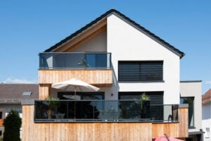 alubalkon vision mit grauem transparentem glas auf einem rustikalen haus